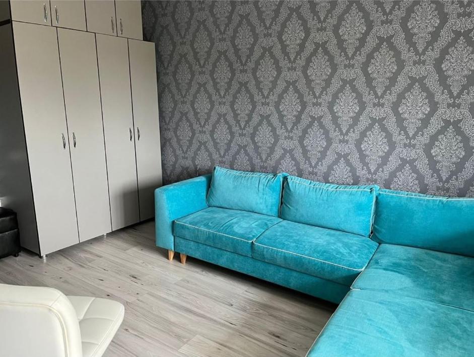 a blue couch in a living room with a wall at Kevin's Guest House in Brăila