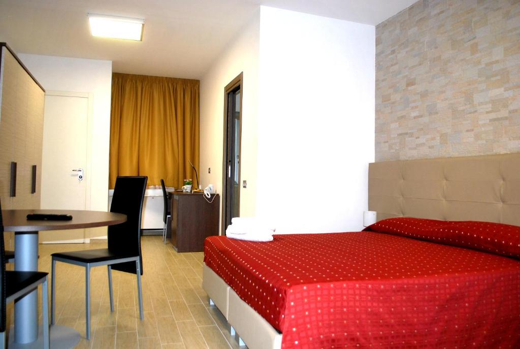 um quarto de hotel com uma cama vermelha e uma mesa em Piazza Dante em Taranto