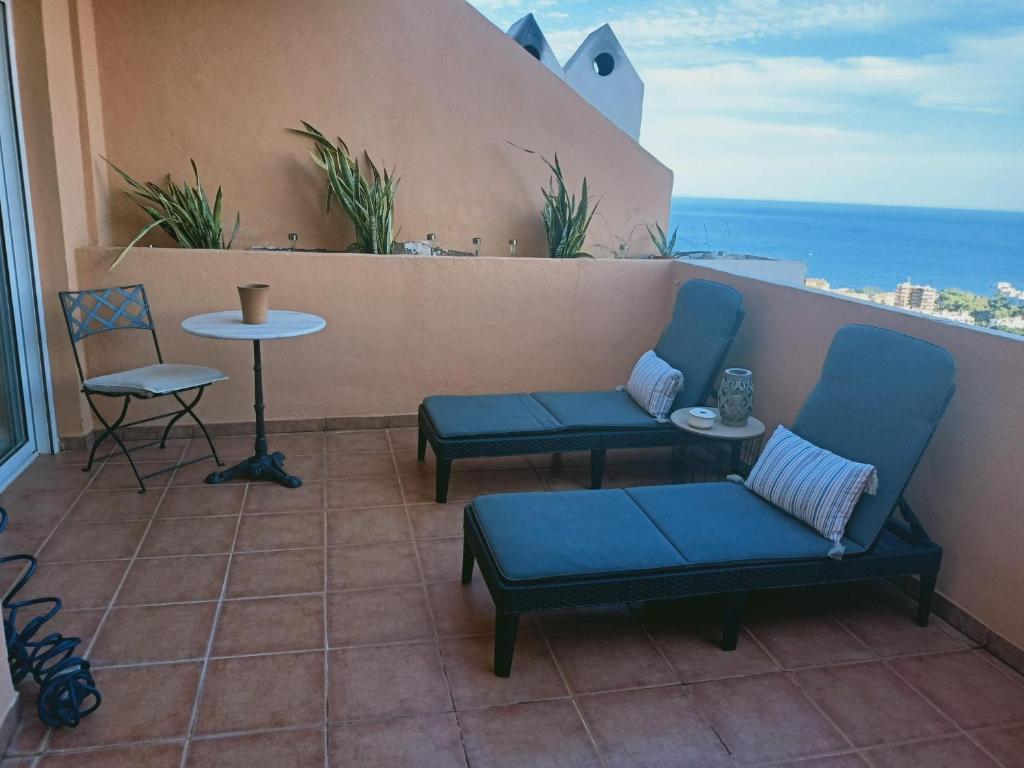 einen Balkon mit zwei blauen Stühlen und einem Tisch in der Unterkunft Habitación con vistas in Aguadulce