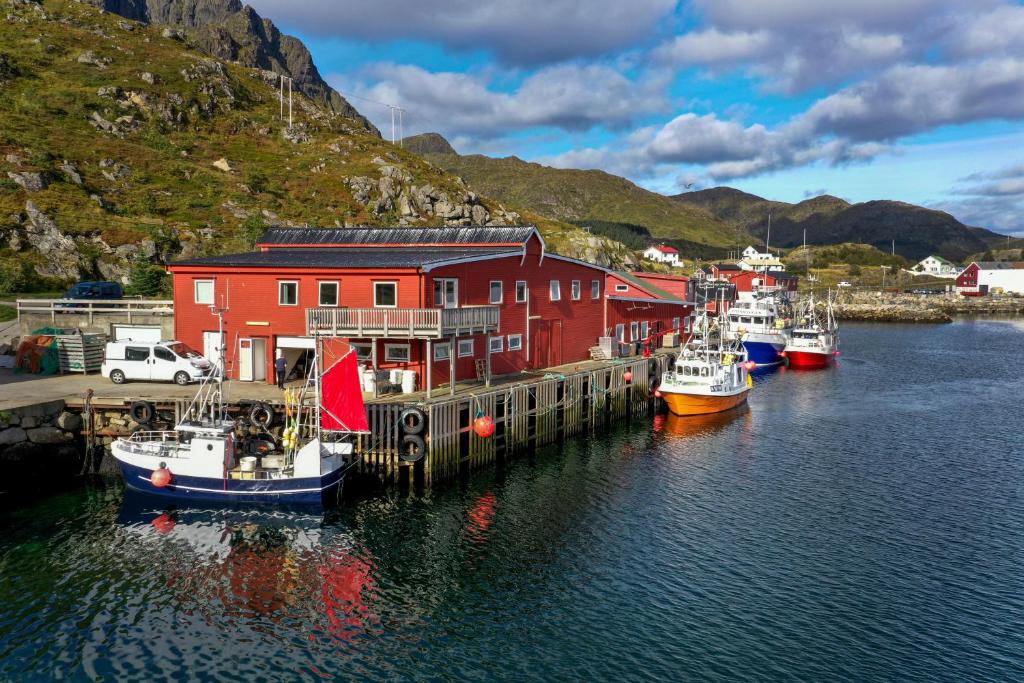 a group of boats docked in a harbor with a red building at Fish factory -The real Lofoten experience in Ballstad