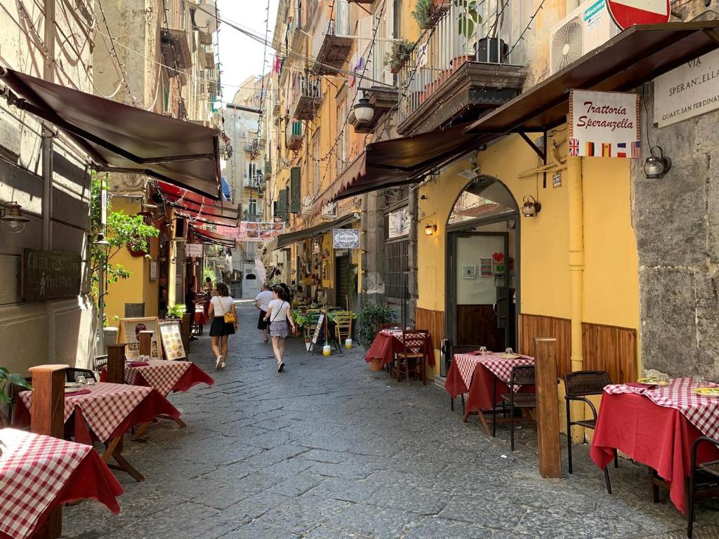 a street with tables and chairs and people walking down a street at White Home Quartieri Spagnoli in Naples