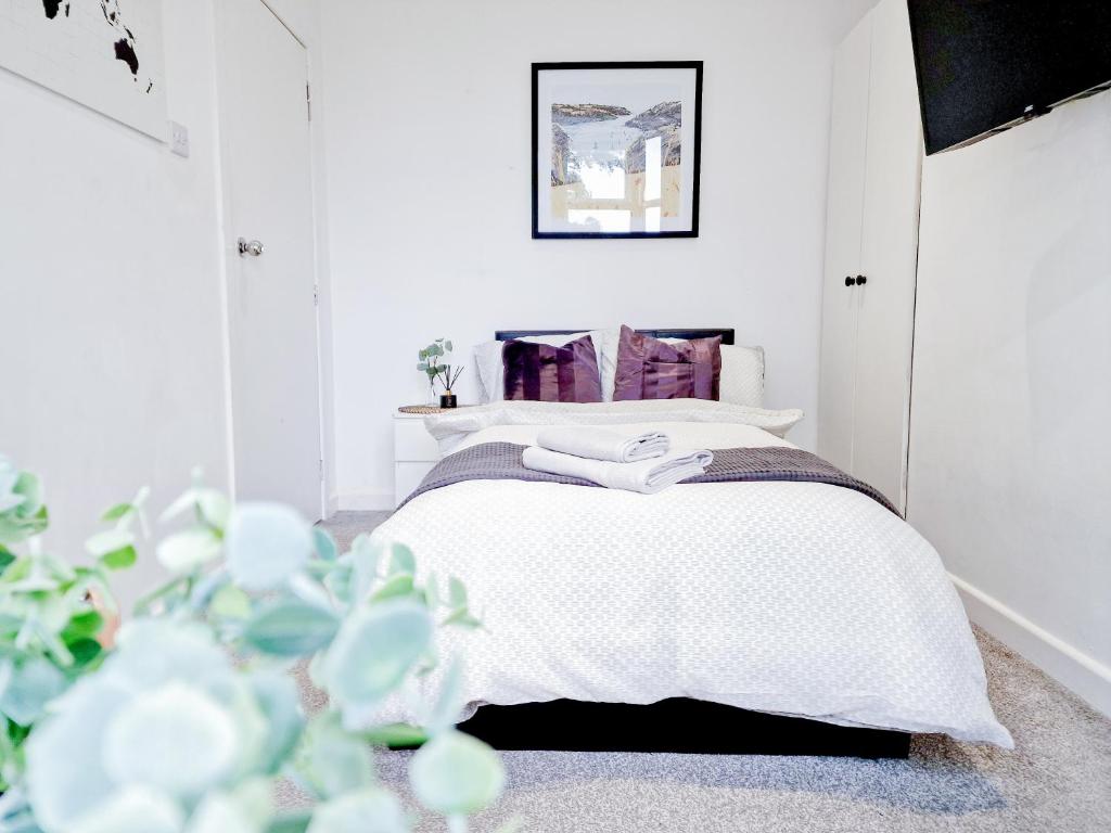 um quarto branco com uma cama branca com almofadas roxas em Tropicana House em Barnsley