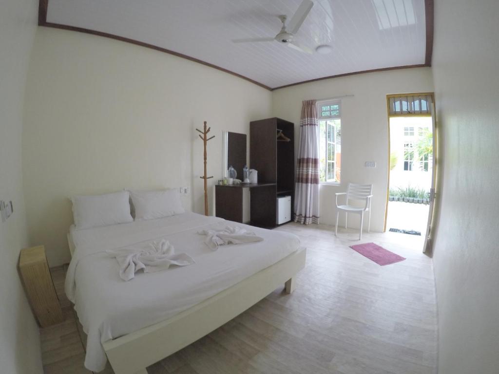 una camera bianca con un letto bianco e un tavolo di Konut by Thakuru a Guraidhoo