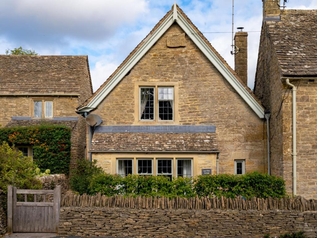 an old brick house with a fence in front of it at Pass the Keys Delightful 4 bedroom Cotswold character cottage in Cheltenham