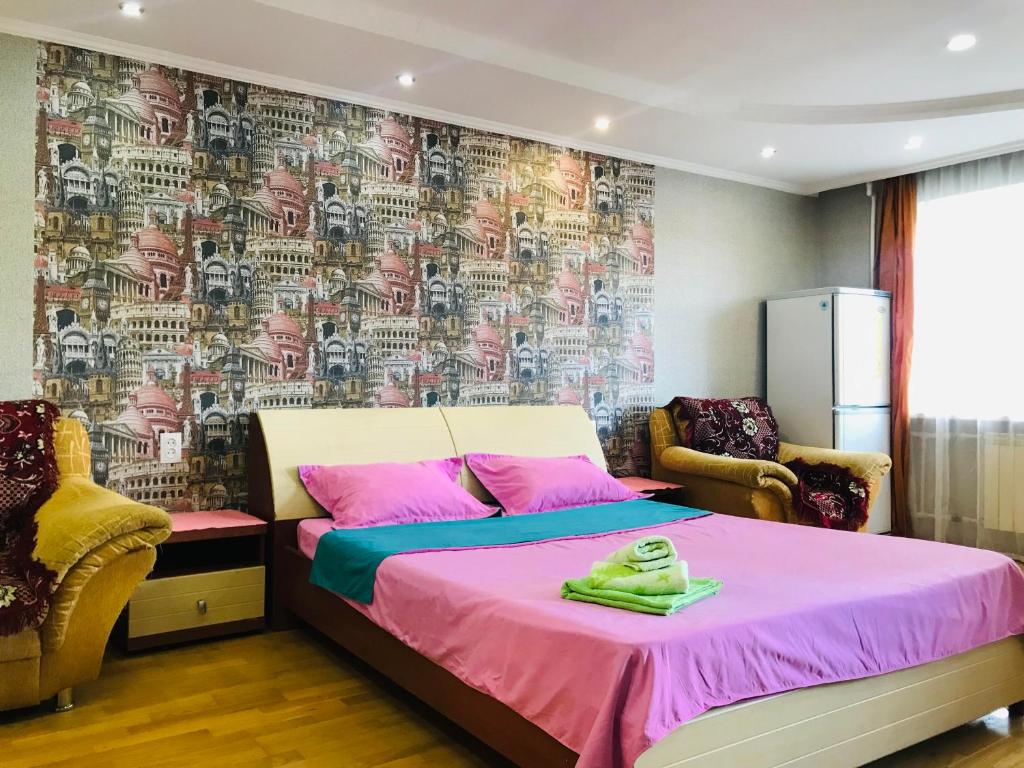 a bedroom with a bed with pink sheets and a wallpaper at Apartments in the city center in Karagandy