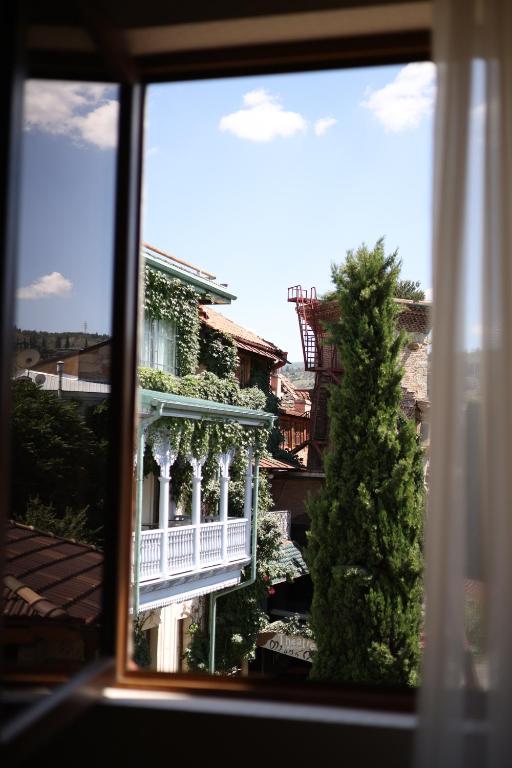 ein Fenster mit Blick auf ein weißes Gebäude mit einem Balkon in der Unterkunft Mukhrantubani Boutique Hotel in Tbilisi City