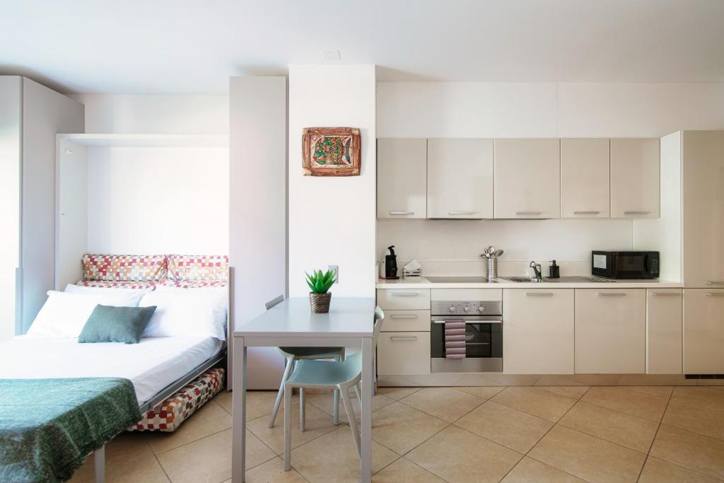 a bedroom with a bed and a table and a kitchen at Prestige 7 by Quokka 360 - quiet studio with balcony in Lugano