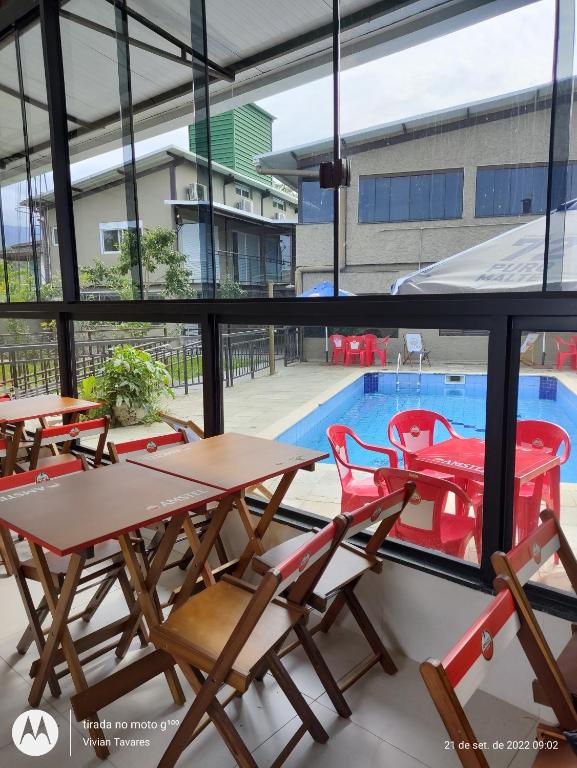 um pátio com mesas e cadeiras e uma piscina em FRANCIS HOTEL MAR em Caraguatatuba