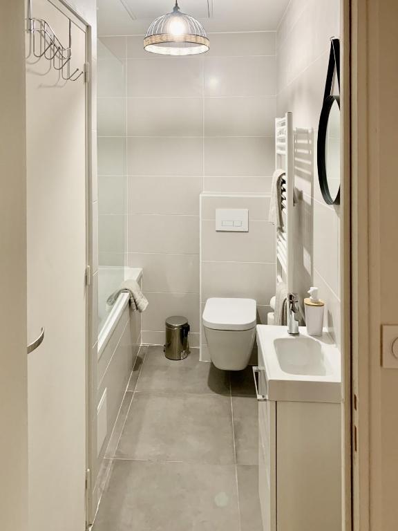 a white bathroom with a toilet and a sink at Perpignan - Appartement en centre ville in Perpignan