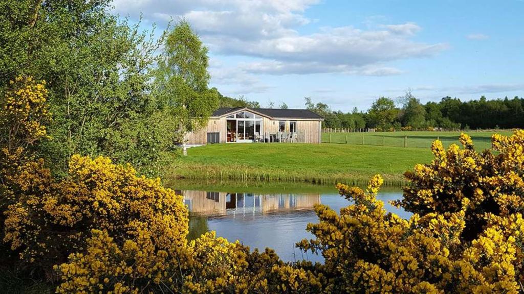 a house sitting next to a body of water at Fern Lodge - Luxury Lodge with steamroom in Perthshire in Perth