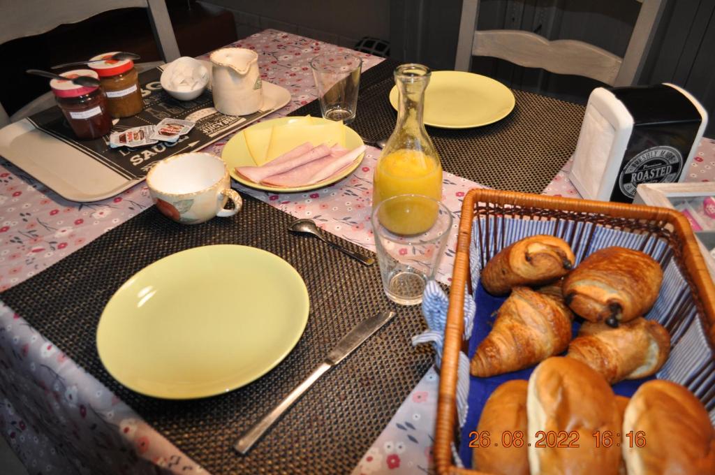 a table with plates and croissants and a basket of bread at Bon séjour in Theux
