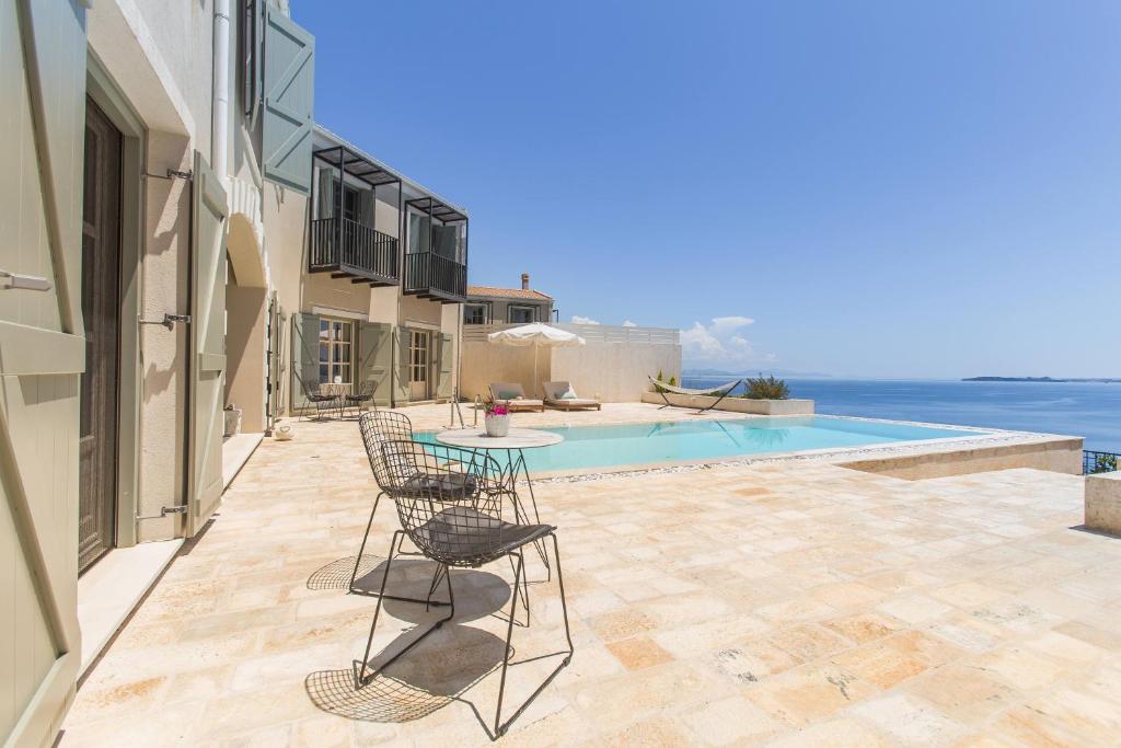a patio with a table and chairs next to a pool at Korypho Villas in Barbati