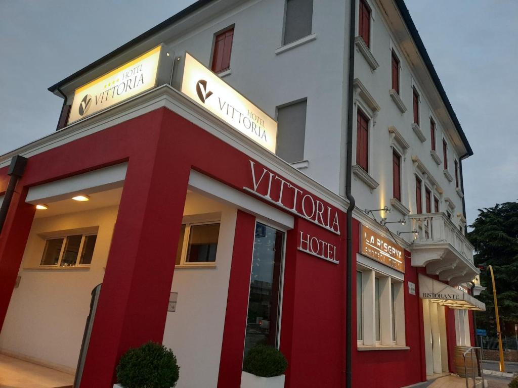 un edificio rojo y blanco con un cartel en él en Hotel Vittoria, en Rubano