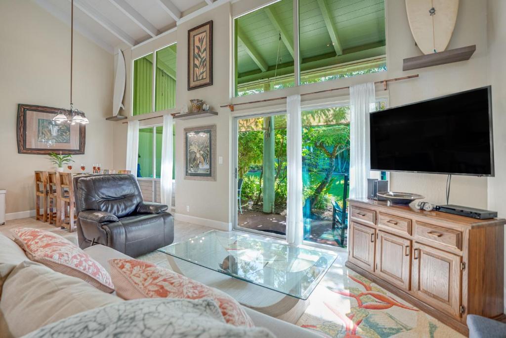 a living room with a tv and a glass table at Puamana 9B in Princeville
