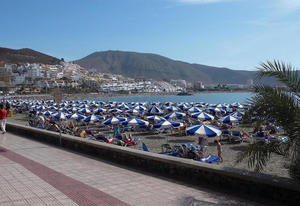 plaża z wieloma błękitnymi i białymi parasolami w obiekcie Vv Los Cristianos centre w mieście Los Cristianos