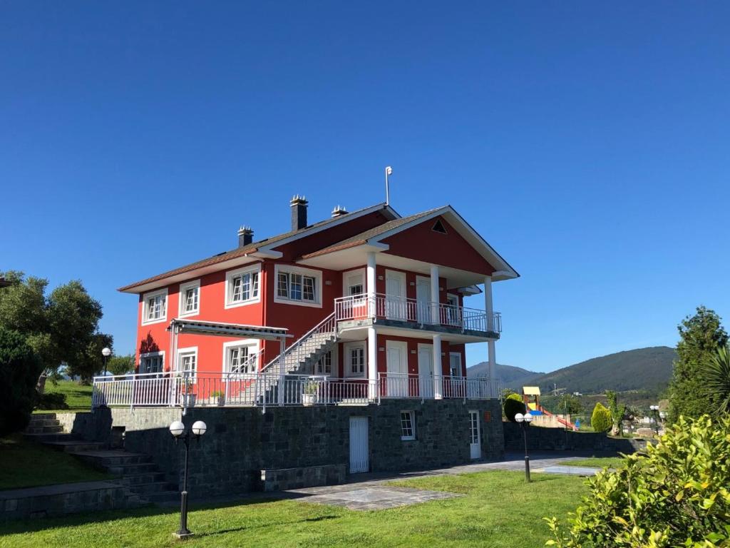 a large red house on top of a stone wall at Apartamentos Montemar in Navia