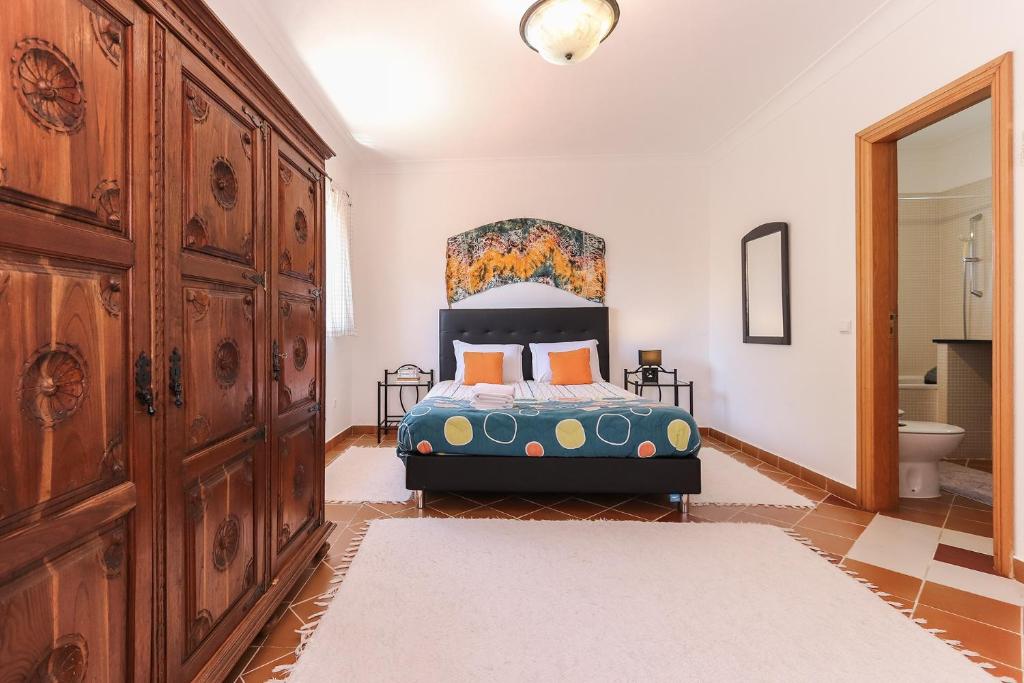 a bedroom with a bed and a large wooden cabinet at Guincho Garden Villa by Homing in Aldeia de Juso