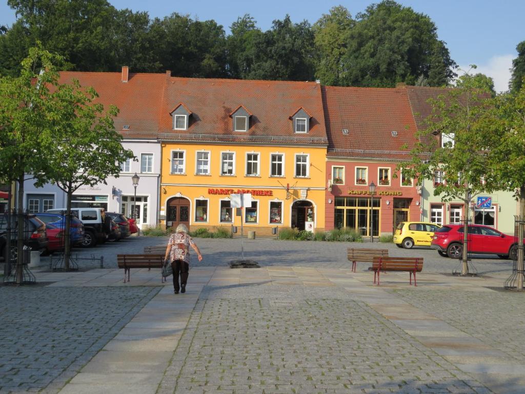 a woman walking in front of a yellow building at Ferienwohnung am Markt in Bad Muskau