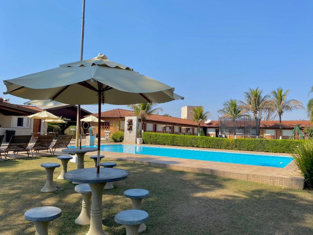 una mesa con sombrilla junto a una piscina en Pousada Mirante das Estancias en Águas de Lindóia