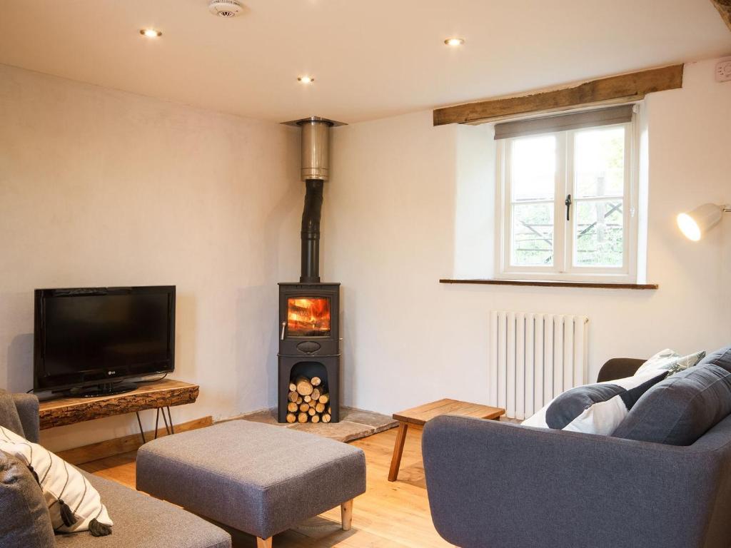 sala de estar con chimenea y TV en The Cider Barn, en Flaxley