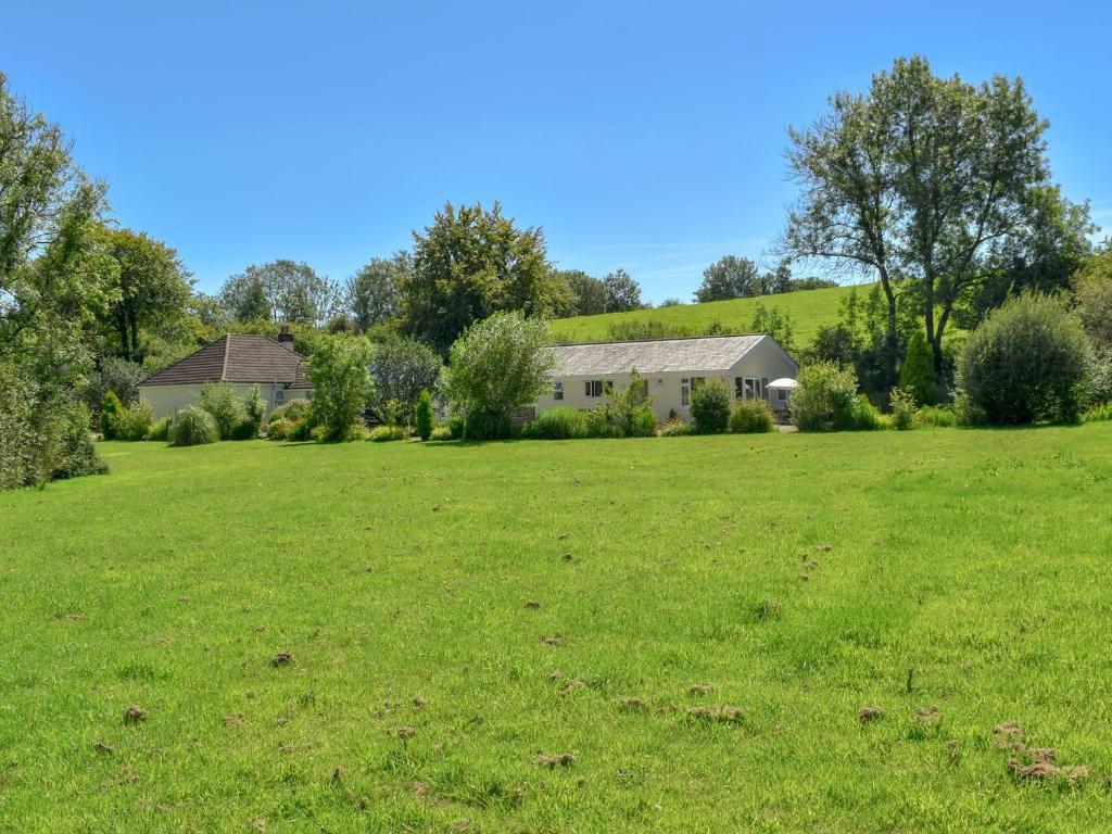 a large green field with a house in the background at Green Valley Retreat in Holsworthy