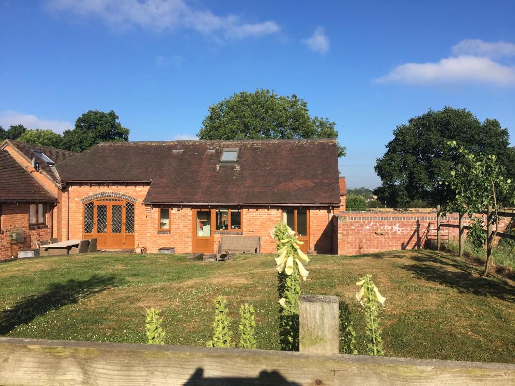 a brick house with a fence in front of it at Coach House at Oaks Barn Farm Alcester with optional hire Salt water hot tub 