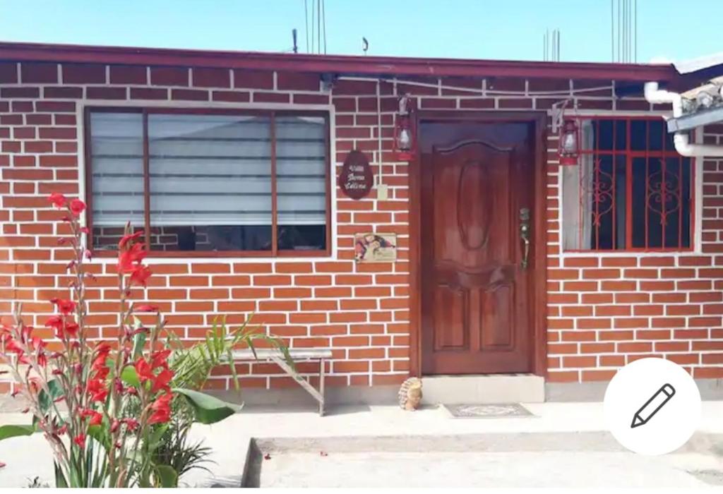 ceglany dom z brązowymi drzwiami i oknem w obiekcie Häuschen nahe Cotopaxi-House near Cotopaxi w mieście Machachi