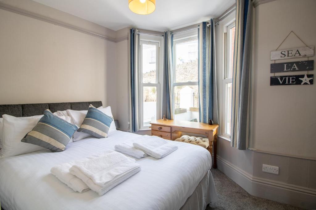 a bedroom with a white bed with pillows and a window at Sea La Vie- Cosy, Modern, Harbourside Views in Brixham