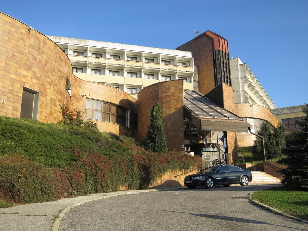 布拉提斯拉瓦的住宿－Retro Hotel Suza，停在大楼前的路上的汽车