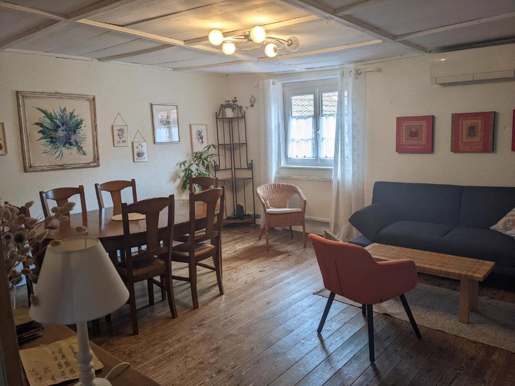 uma sala de estar com um sofá, uma mesa e cadeiras em Gîte de charme au coeur du vignoble alsacien em Bernardvillé