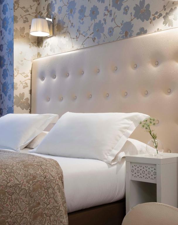 a bedroom with a white bed with a large headboard at Hôtel Plaza Étoile in Paris