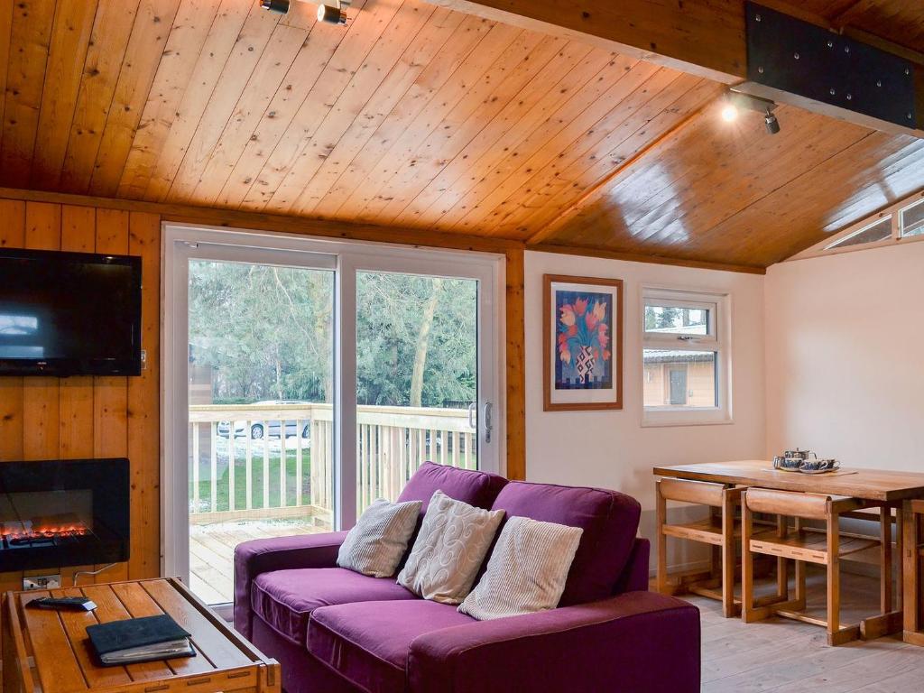 a living room with a purple couch and a wooden ceiling at Cedar Lodge in Ellington