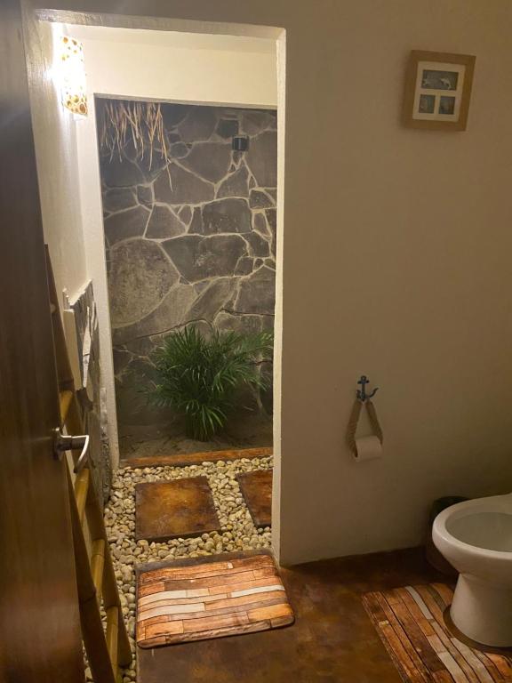 a bathroom with a toilet and a stone wall at Coconi House in Tuxpan de Rodríguez Cano