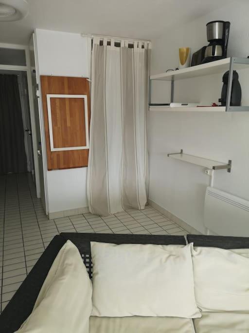 a room with a bed with pillows and a curtain at Résidence arc en ciel, proche de la plage accés direct ,internet et parking privatif gratuit in La Grande Motte