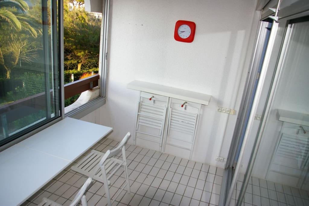 a white room with a white table and a red clock at Résidence arc en ciel, proche de la plage accés direct ,internet et parking privatif gratuit in La Grande Motte