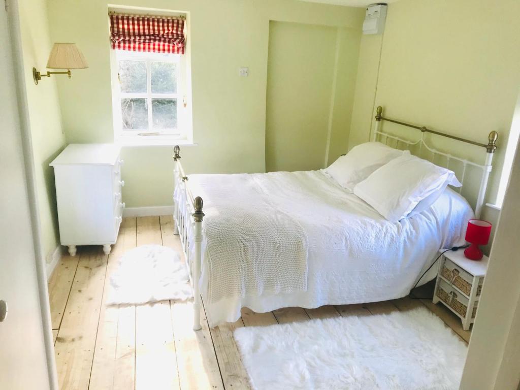a bedroom with a white bed and a window at Beautiful Somerset Cottage with garden views. in Bruton