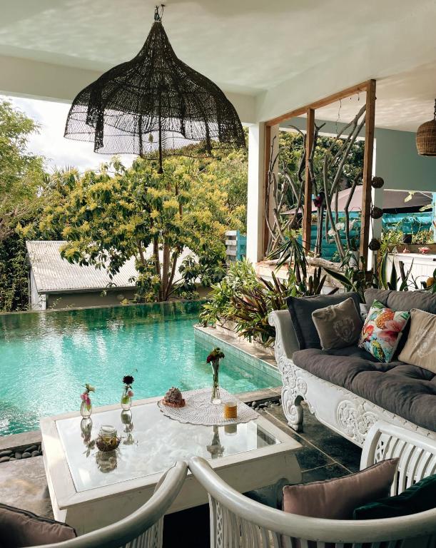 een woonkamer met een bank, een tafel en een zwembad bij Chambres d'hôtes & spa Le Jardin de Ravintsara in Ravine des Cabris