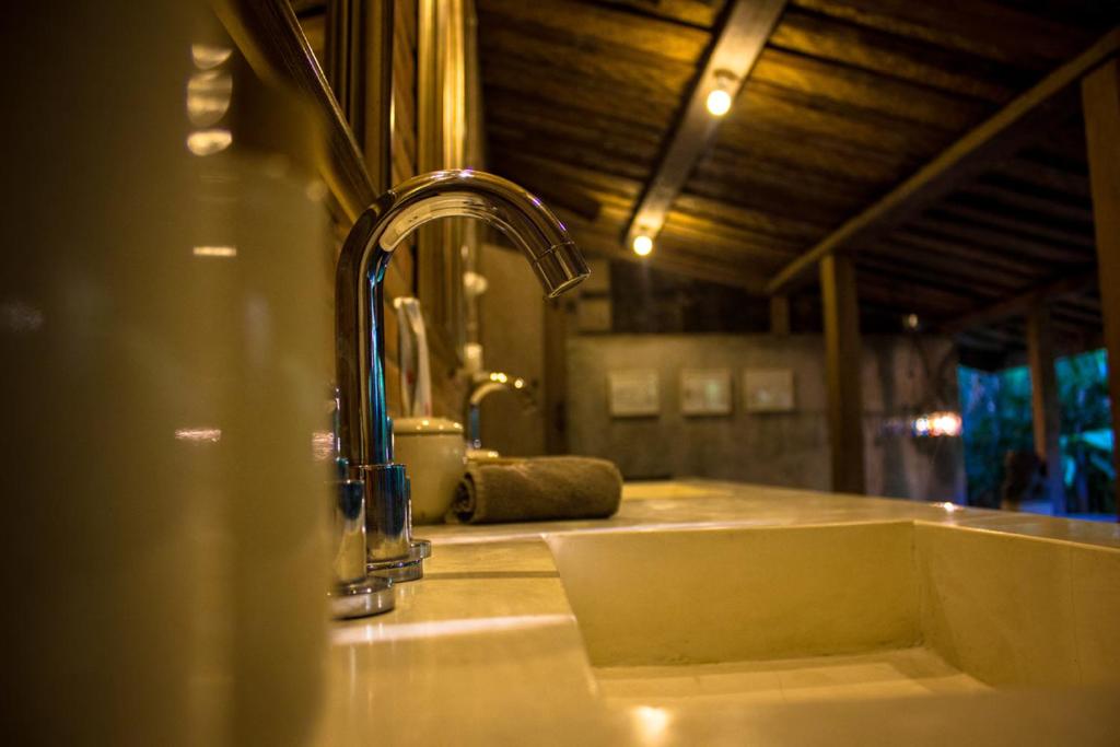 een wastafel in de badkamer met een kraan en een spiegel bij Wahyu Private Lux Joglo Ideal For Couples W Pool in Seminyak
