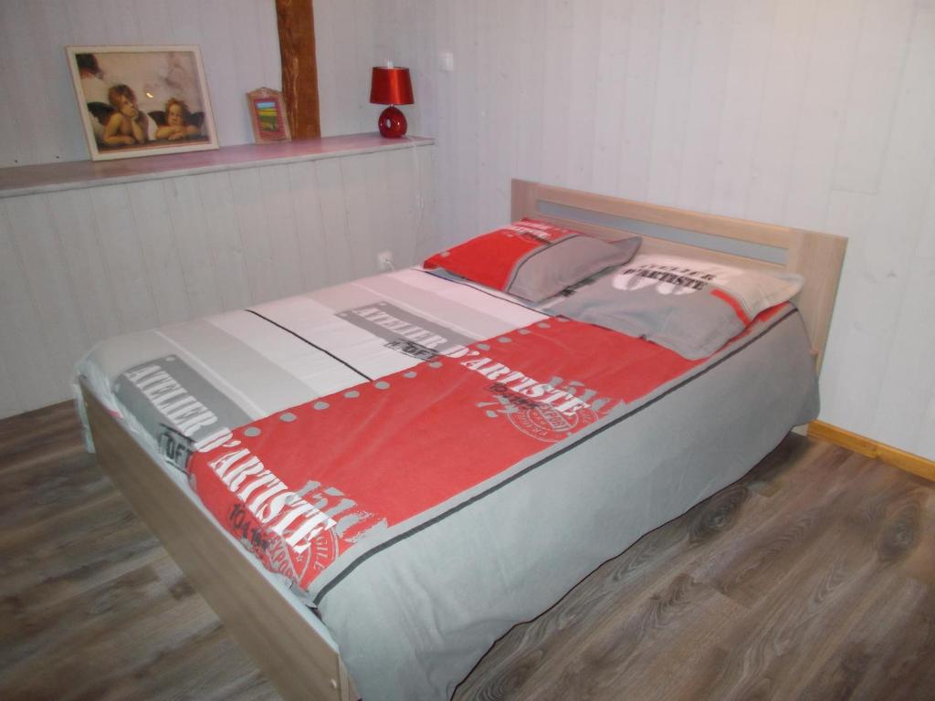 a bed with a red and white blanket on it at La Ferme de Genarville in Bouville