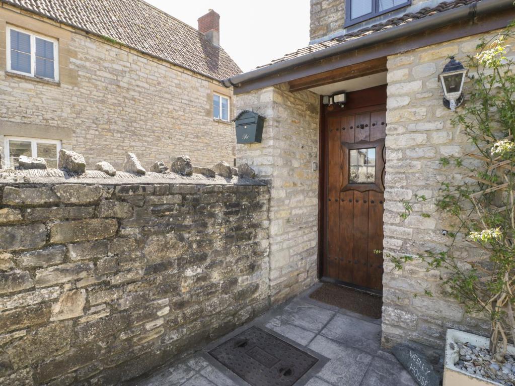 a brick building with a wooden door and a stone wall at Wesley House in Shepton Mallet
