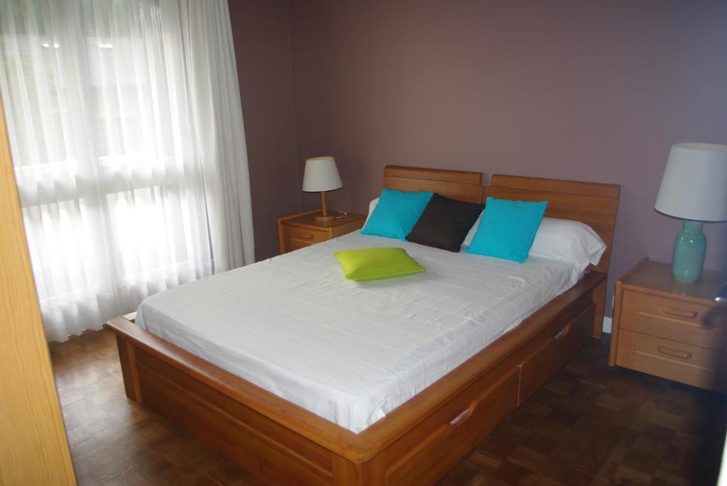 a bedroom with a bed with blue and green pillows at Appartement Résidence du Lac in Saint-Jean-de-Luz