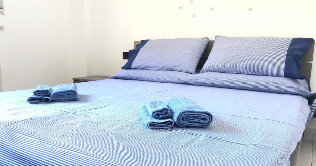 een bed met blauwe handdoeken en slippers erop bij Appartamento moderno esclusivo vicino stazione e centro città in Alessandria