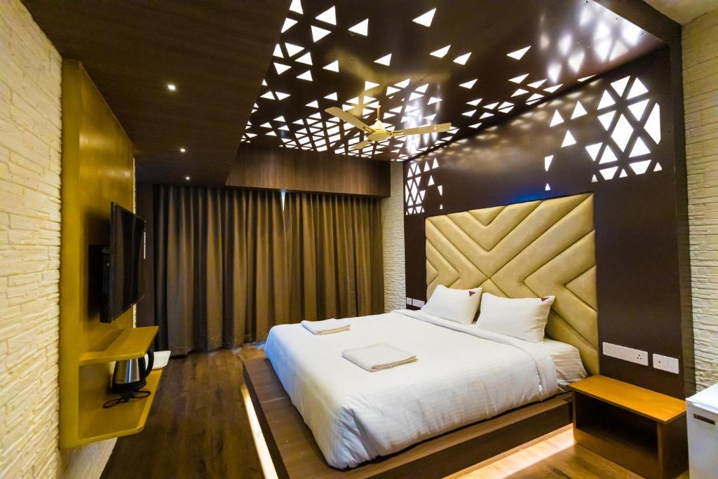 1 dormitorio con 1 cama grande y TV en HOTEL VIJAYARANI, en Tiruchchirāppalli