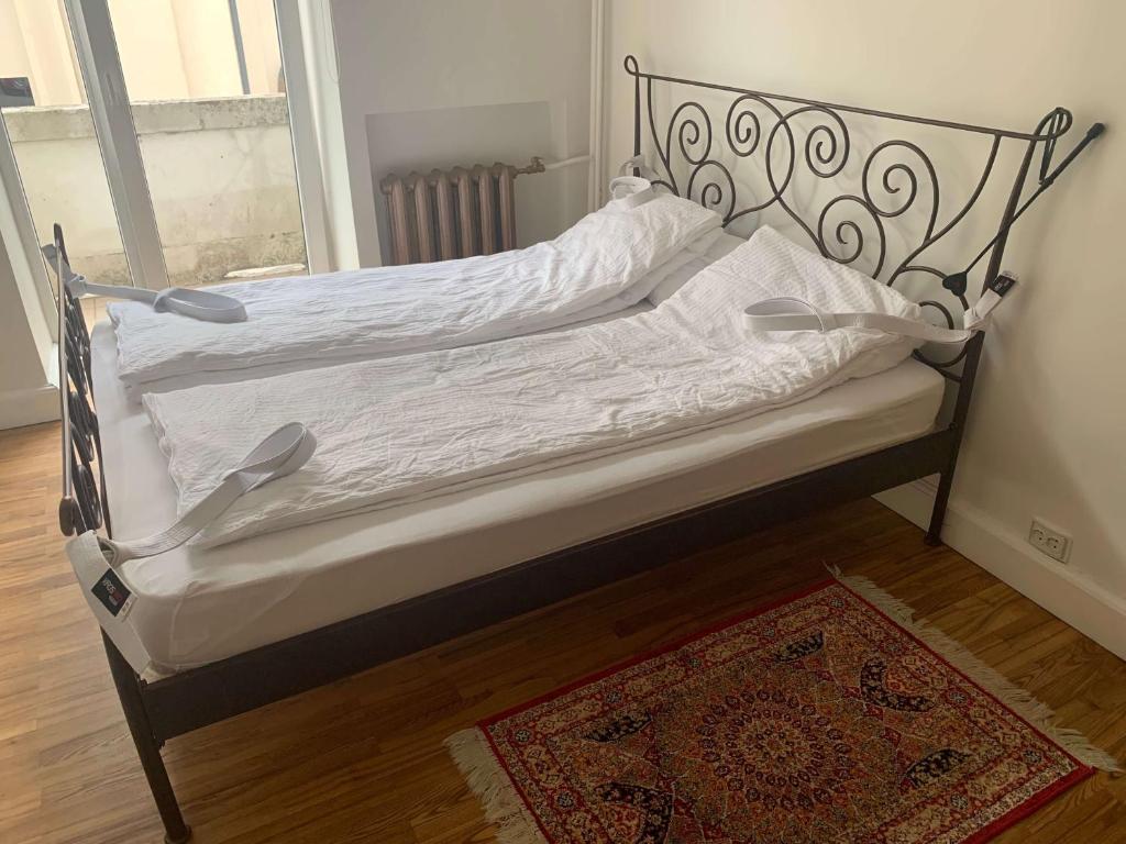 a bed with white sheets and a metal frame at Modern 2-room flat in the city center in Šiauliai