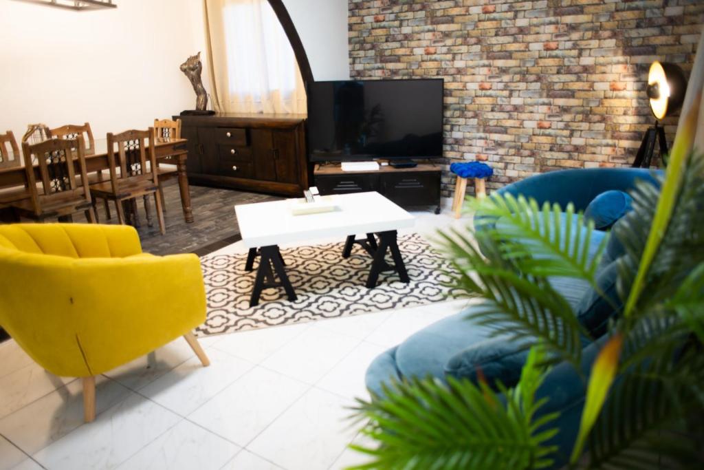 een woonkamer met een bank, een tafel en een tv bij Le Bambou T3 Centre ville Sainte Clotilde Rez de jardin in Bois de Nèfles
