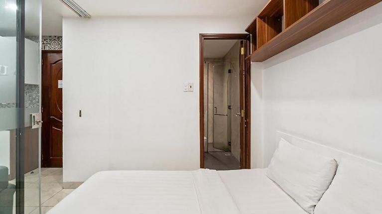 um quarto com uma cama branca e uma porta de vidro em HANZ Premium Hotel Sakura em Cidade de Ho Chi Minh