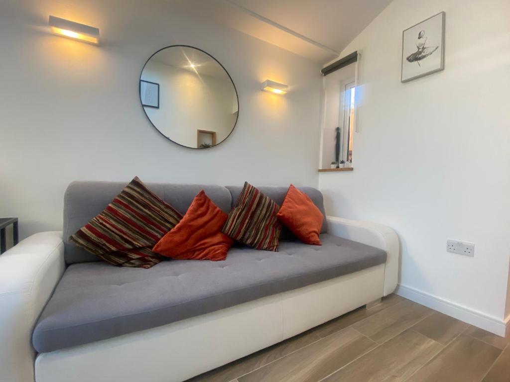 un sofá con almohadas y espejo en Lovely and Modern Studio Apartment. en Borehamwood
