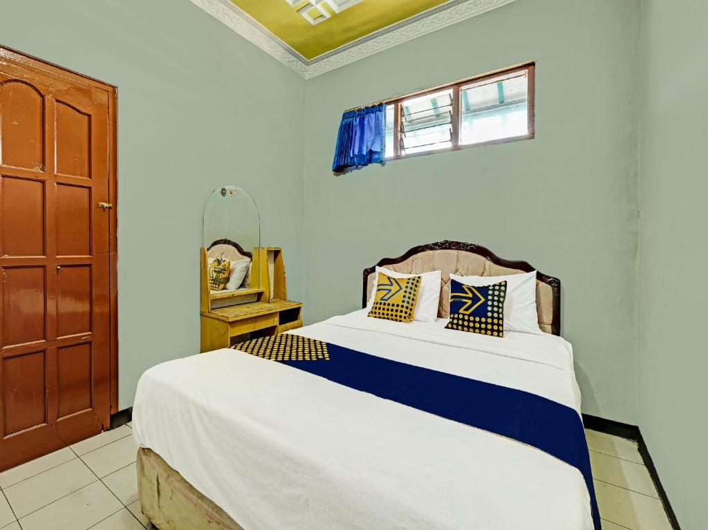 1 dormitorio con 1 cama con sábanas azules y blancas en SPOT ON 91715 Hotel Citra Dewi 1, en Semarang
