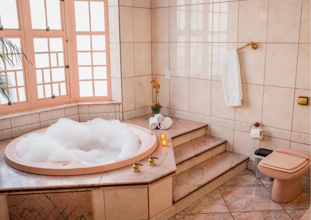a bathroom with a tub and a toilet at Rogai Hotel Pousada in Aparecida