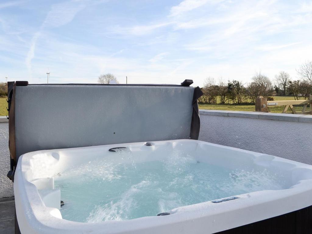 a bath tub filled with blue water on a balcony at Greengill Farm Holiday Cottage - Ukc2768 in Gilcrux